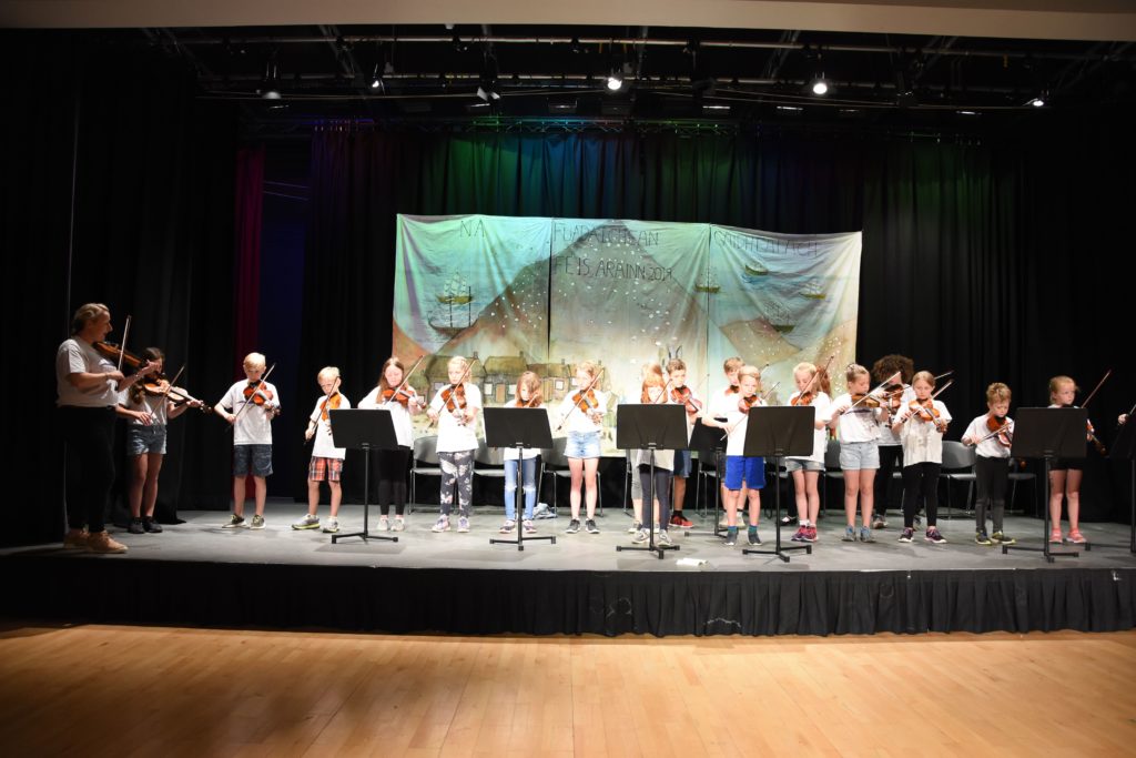 Gillian Frame leads a large class of fiddlers who impressed the audience at the concert finale.