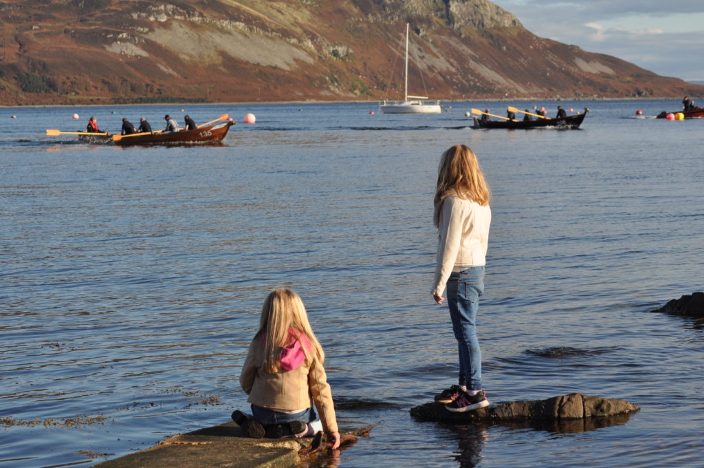 Two young girls watch the action from the seashore.
