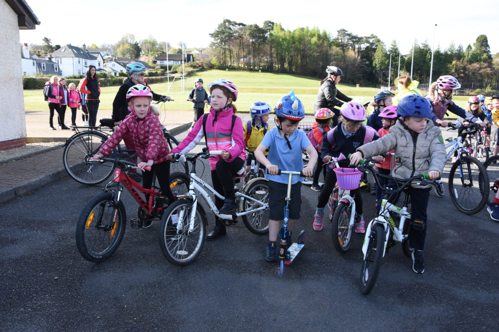 Younger children gather with their scooters and bikes.