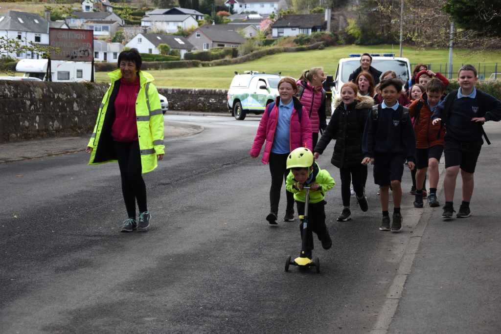 Walking pupils bring up the rear of the procession to school.