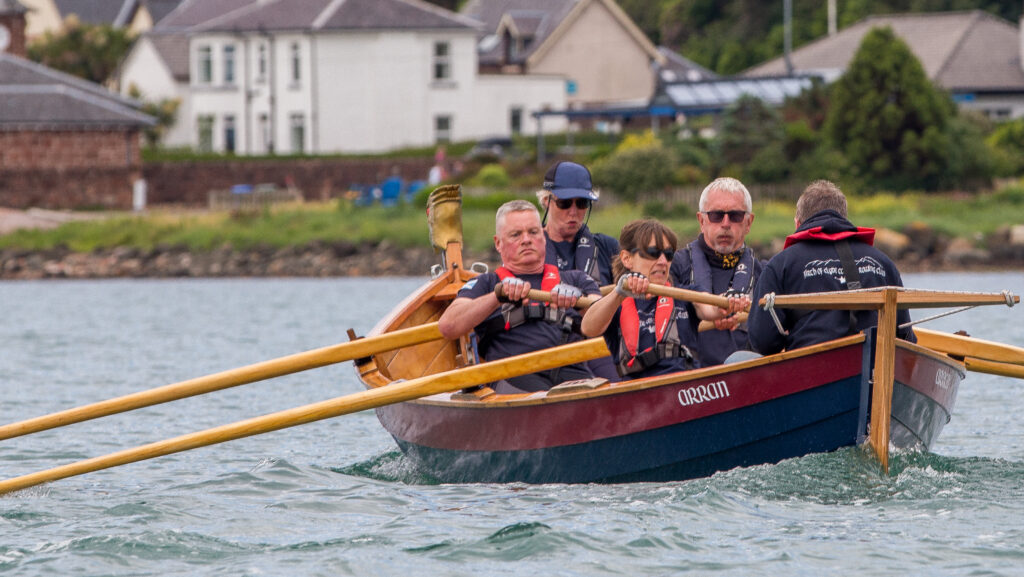 Determination on the faces of Firth of Clyde rowers in the Arran skiff.