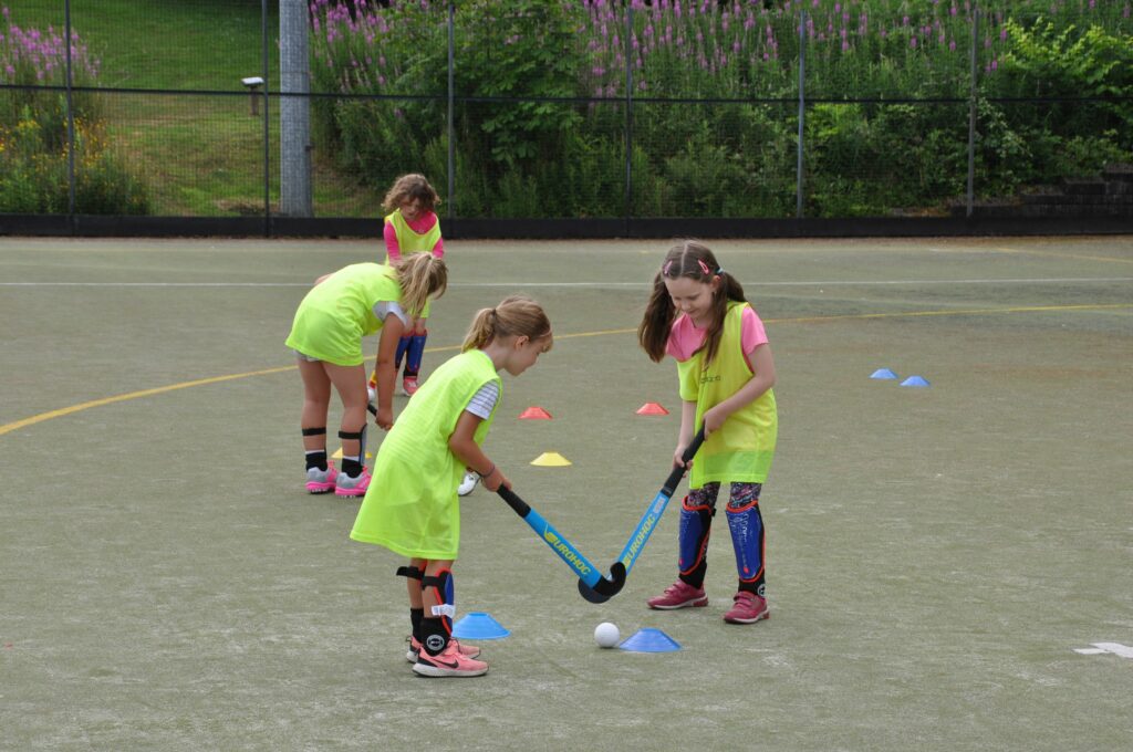Young girls get to grips with their hockey sticks.