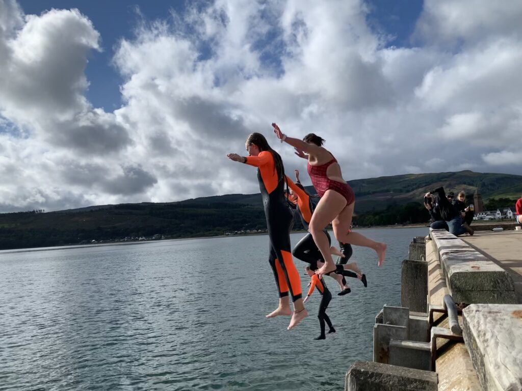Georgina leaps off the Lamlash Pier with some of her young students and supporters. Photograph: COAST.
