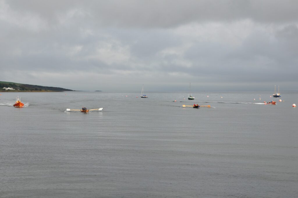 Finalists race towards the finish line flanked by the RNLI lifeboat and another support vessel.