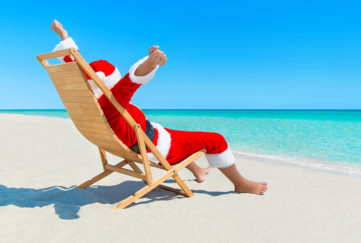 Christmas Santa Claus hands up enjoy sun on deck chair Pic: Istockphoto