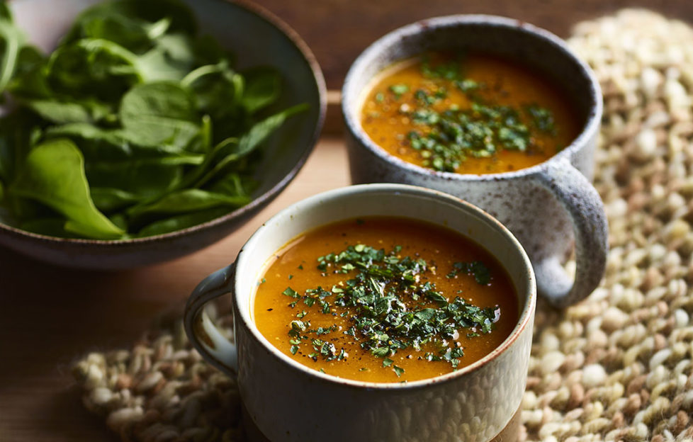WW recipe: 2 earthenware cups of spiced carrot & ginger soup, garnished with herbs, bowl of fresh spinach on the side