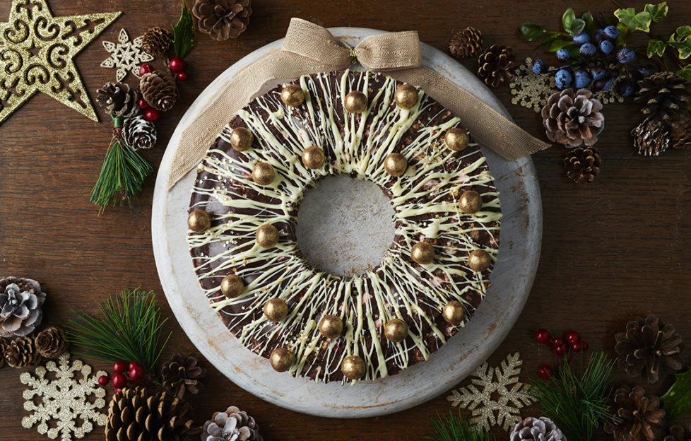 Rocky Road wreath, solid chocolate ring drizzled with white chocolate, studded with gold dusted chocolate sweets and garnished with a fabric bow