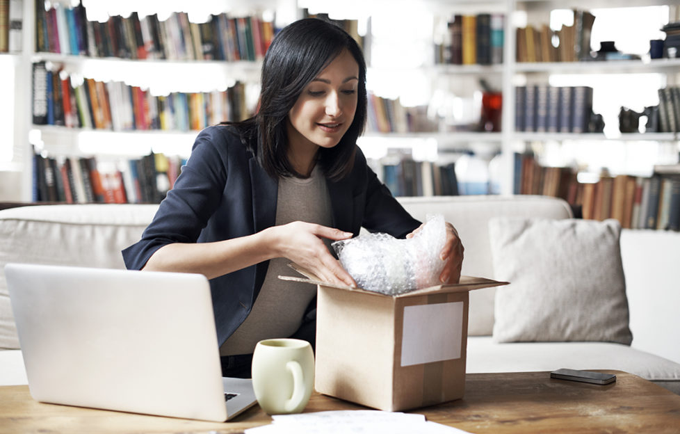 Woman preparing parcel for shipment in her cozy loft apartment