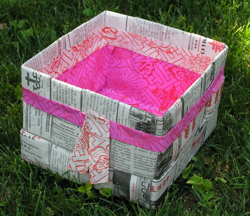 Box covered in newspaper and lined with bright pink paper