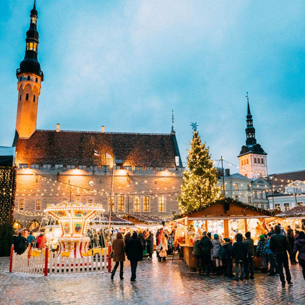 Beautiful stone building with fairground rides and stalls in foreground