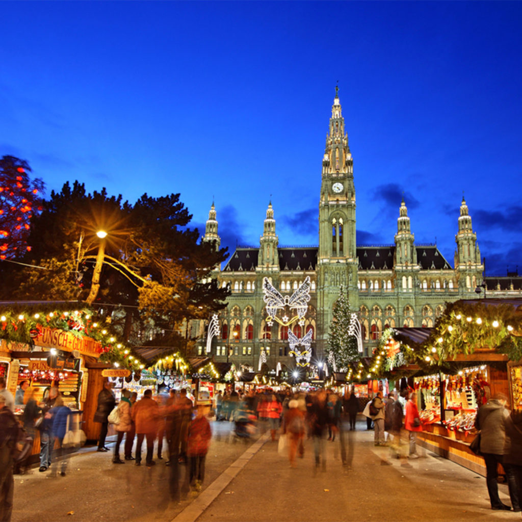 Turreted building against royal blue sky, Christmas market stalls in foreground