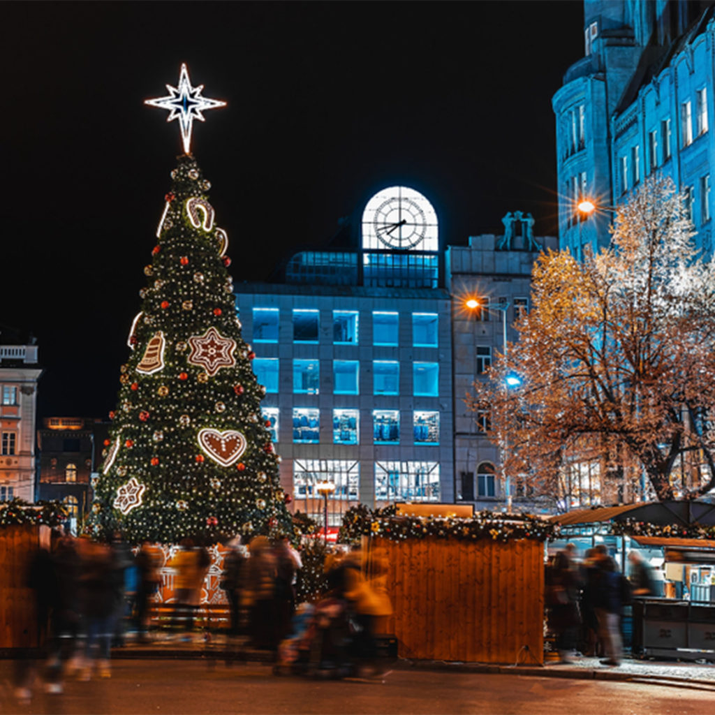 Christmas tree with large heart designs, floodlit buildings around