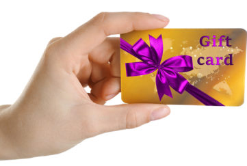 Woman's hand holding gift card decorated with purple ribbon