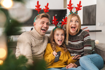 Cheerful family sitting together on a couch at the living room at Christmas
