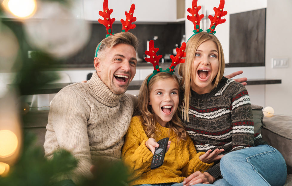 Cheerful family sitting together on a couch at the living room at Christmas