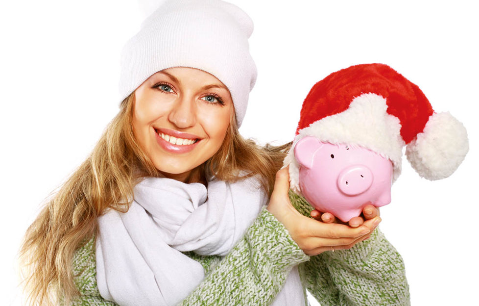 Lady holding piggy bank wearing santa hat Pic: Shutterstock