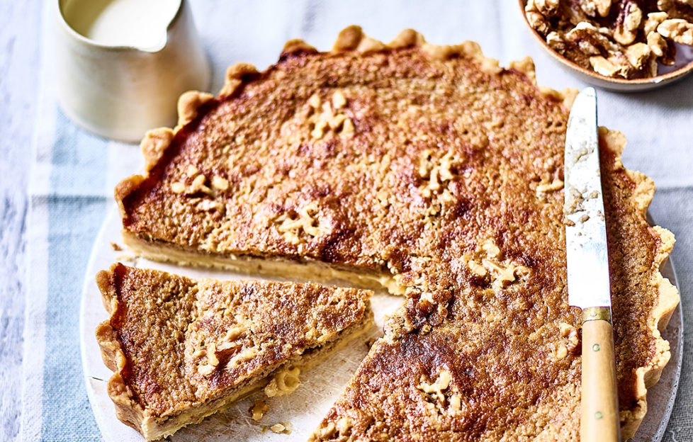 Golden brown flan with walnuts embedded in egg mixture, one slice cut