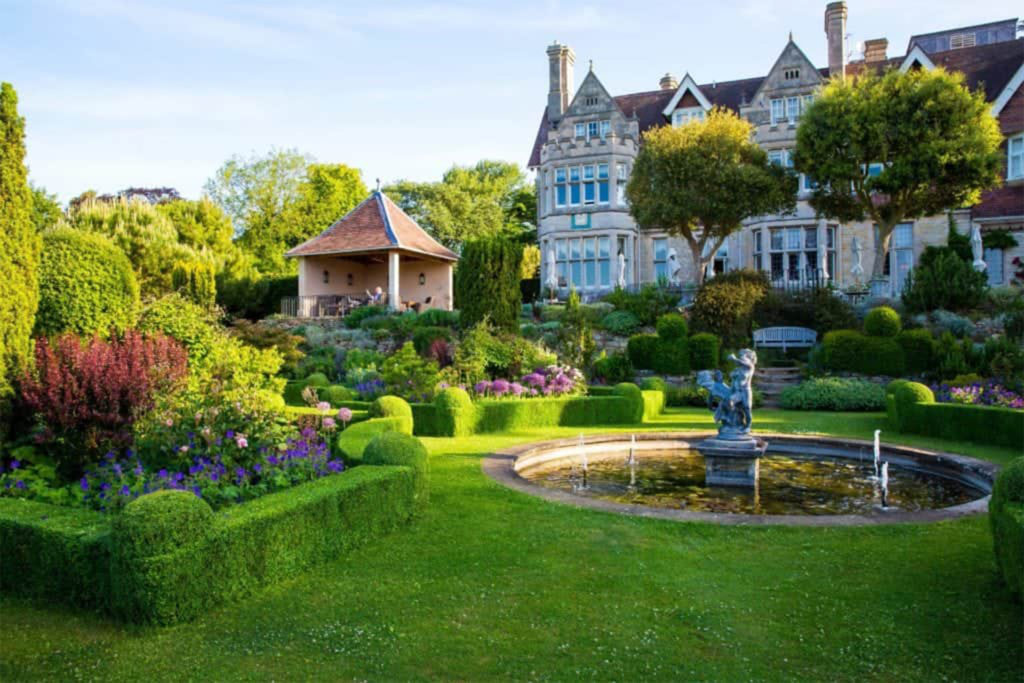 Ornately plastered house with bay windows, seen from gardens with fountain