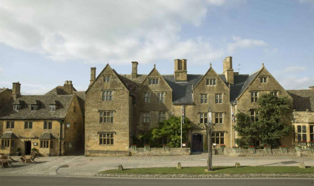 Traditional yellow/grey stone building, stone mullioned windows and tall chimneys