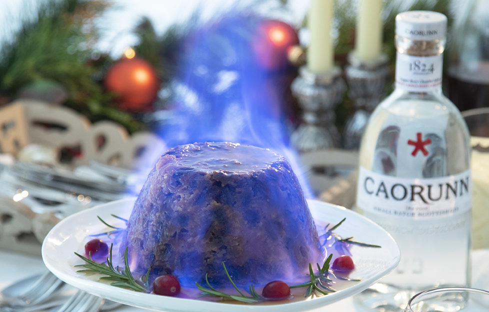 Christmas pudding enveloped in blue flame, bottle of Caorunn gin to the side