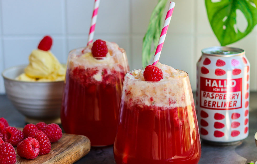 2 glasses of raspberry and beer cocktail topped with ice cream and a raspberry, striped drinking straws