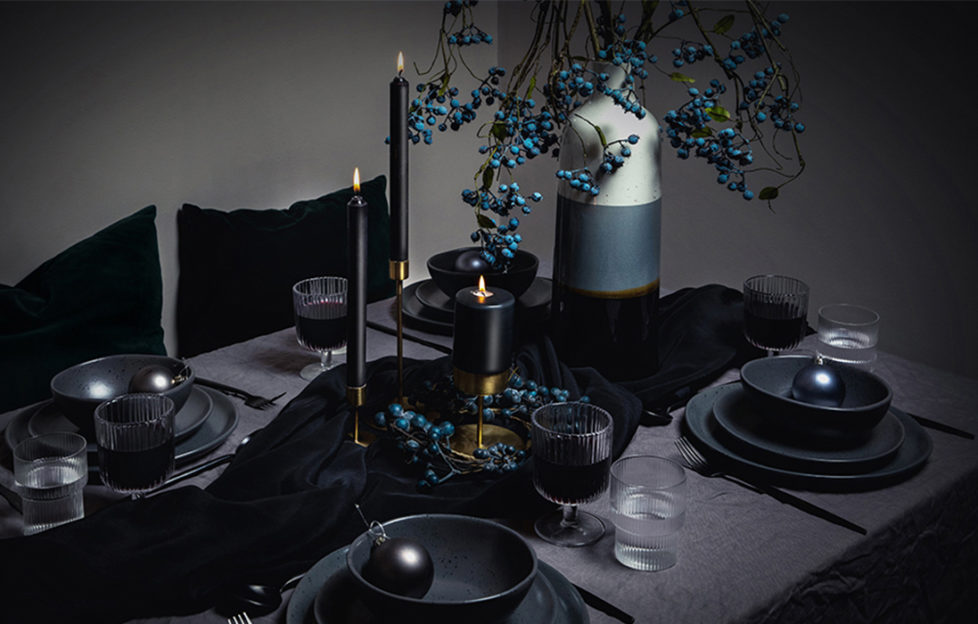 Dark themed Christmas tablescaping with black candles and blue faux berries