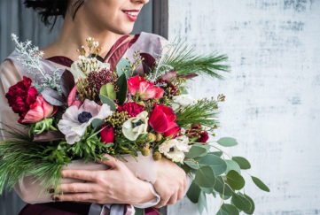 woman with armful of beautiful Christmas flowers in red and white
