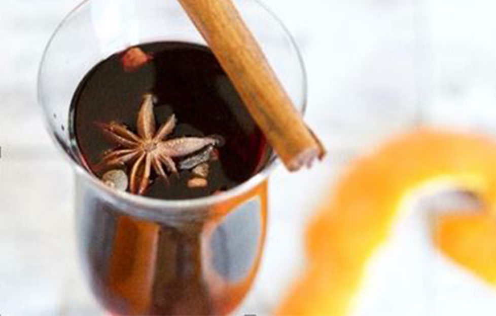 glass of mulled rose wine with cinnamon stick, star anise and orange peel