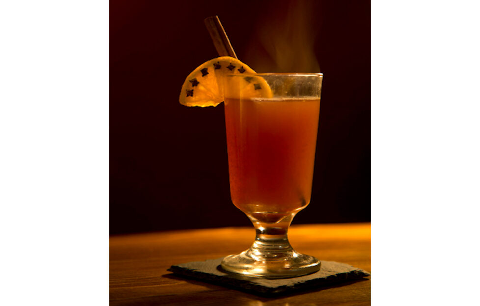 Glass of steaming Wassail drink on dark background