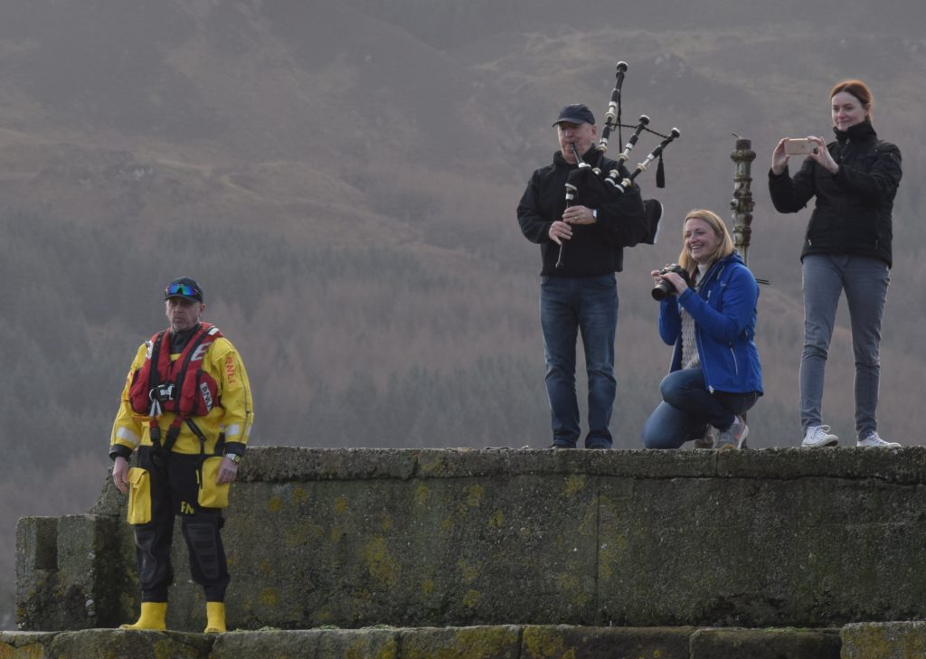 Piper Ian McKerral offered encouragement as safety officials stood by and spectators snapped photographs.