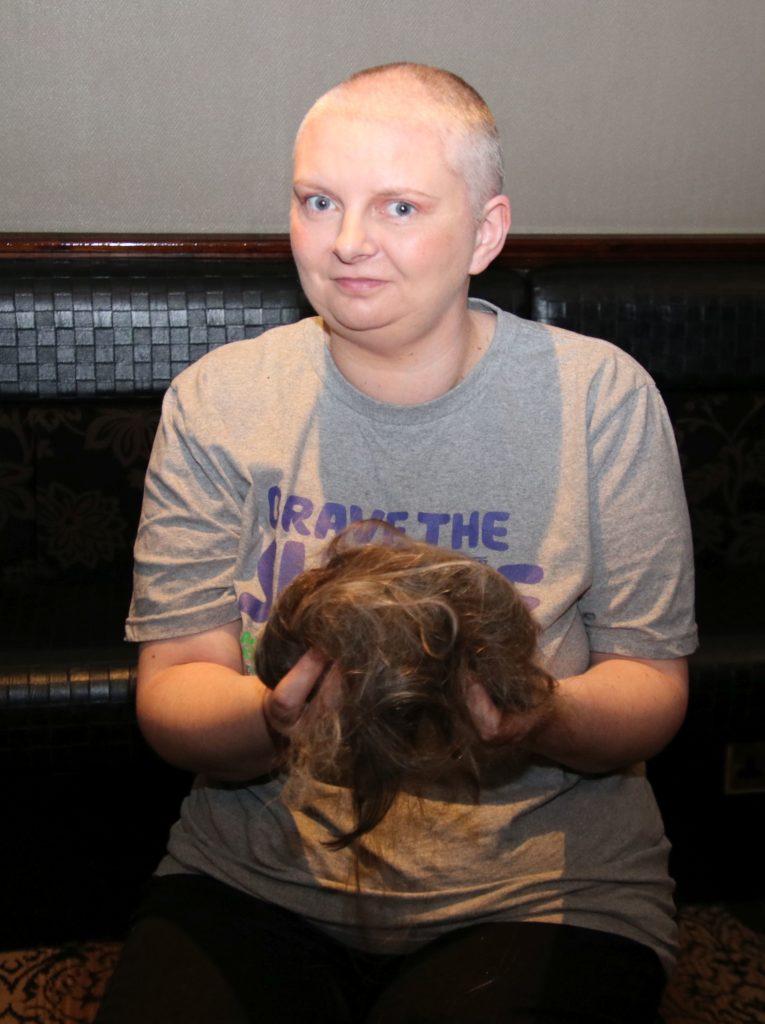 Joanna, sporting her Brave the Shave T-shirt, holds the hair that was cut from her head.