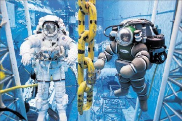 HELLO MATEY: An astronaut in his underwater-adapted spacesuit, left, takes time out of his mission training to pose with a deepsea diverin his Atomspheric Dive System (ADS) during a offshore platform testing session at NASA’ Neutral Buoyancy Lab