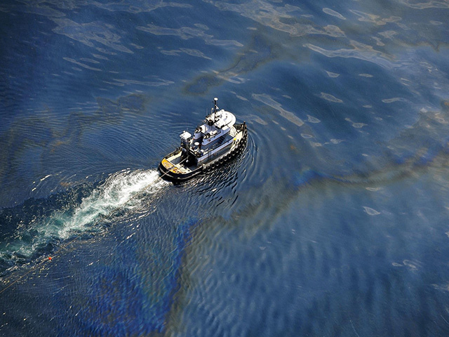 A boat moves through oily water at the site of the Deepwater Horizon oil spill in the Gulf of Mexico