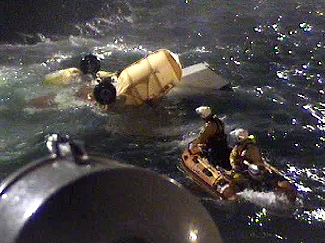 RNLI volunteers approach the helicopter's yellow floatation device to inspect the wreckage.