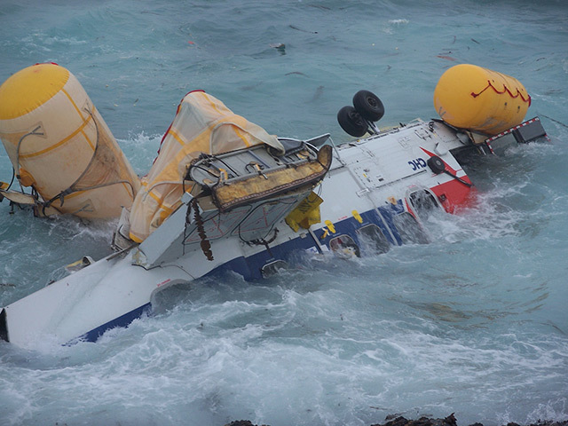 Wreckage of the helicopter after the August crash which killed four people is buffeted by the surf off the Shetland mainland