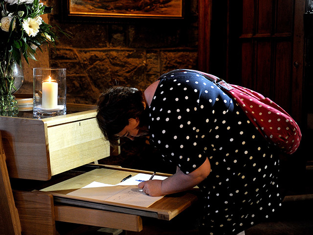 A visitor to St Nicholas Church signs the book of condolence for the Super Puma crash victims.