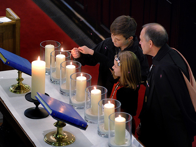 Calum and Isla Mooney light a candle in memory of their dad Eamonn Martin Mooney. Pic: Colin Rennie