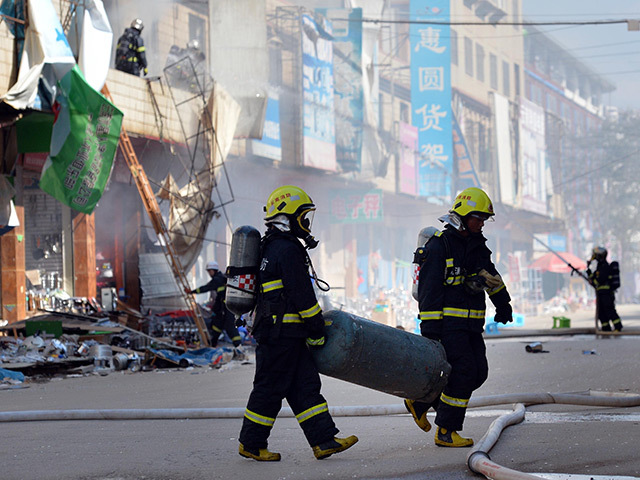 Firemen lift wreckage from the site of the explosion.