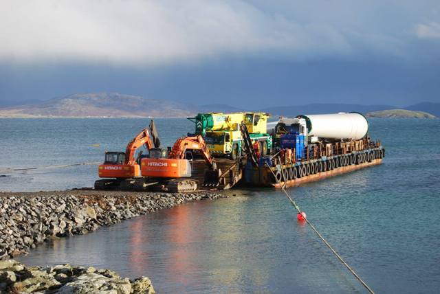 A barge transports part of the turbine to the site