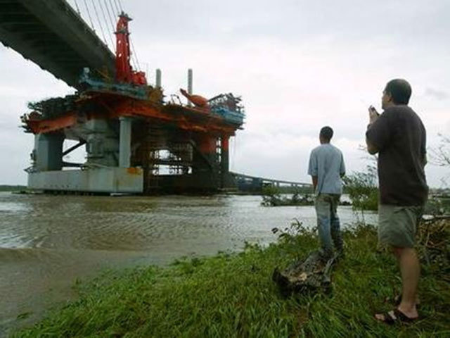 DEVASTATION: People gather to watch  a drilling rig that broke adrift during Hurricane Katrina