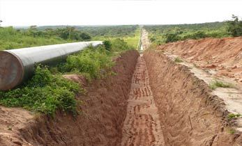 Trench with brown earth between fields stretches into distance