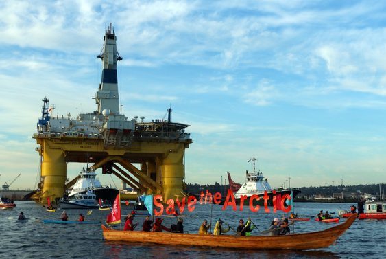 Environmental activists in canoes blocking a rig's path.