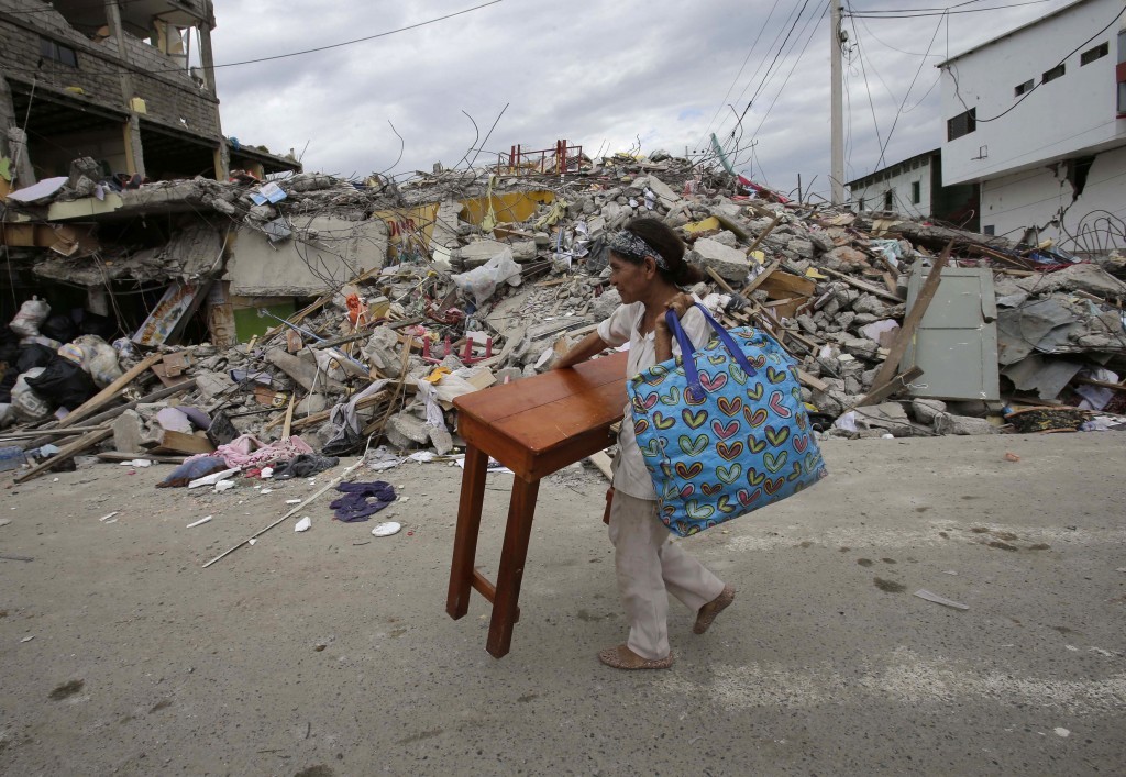 A woman carries a table through the street after an earthquake in Pedernales, Ecuador, Sunday, April 17, 2016. Rescuers pulled survivors from the rubble Sunday after the strongest earthquake to hit Ecuador in decades flattened buildings and buckled highways along its Pacific coast on Saturday. The magnitude-7.8 quake killed hundreds of people.