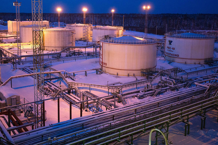 Oil storage tanks stand illuminated at night in the central processing plant for oil and gas at the Salym Petroleum Development oil fields near the Bazhenov shale formation in Salym, Russia, on Tuesday, Feb. 4, 2014. Salym Petroleum Development, the venture between Shell and Gazprom Neft, has started drilling the first of five horizontal wells over the next two years that will employ multi-fracturing technology, according to a statement today. Photographer: Andrey Rudakov/Bloomberg