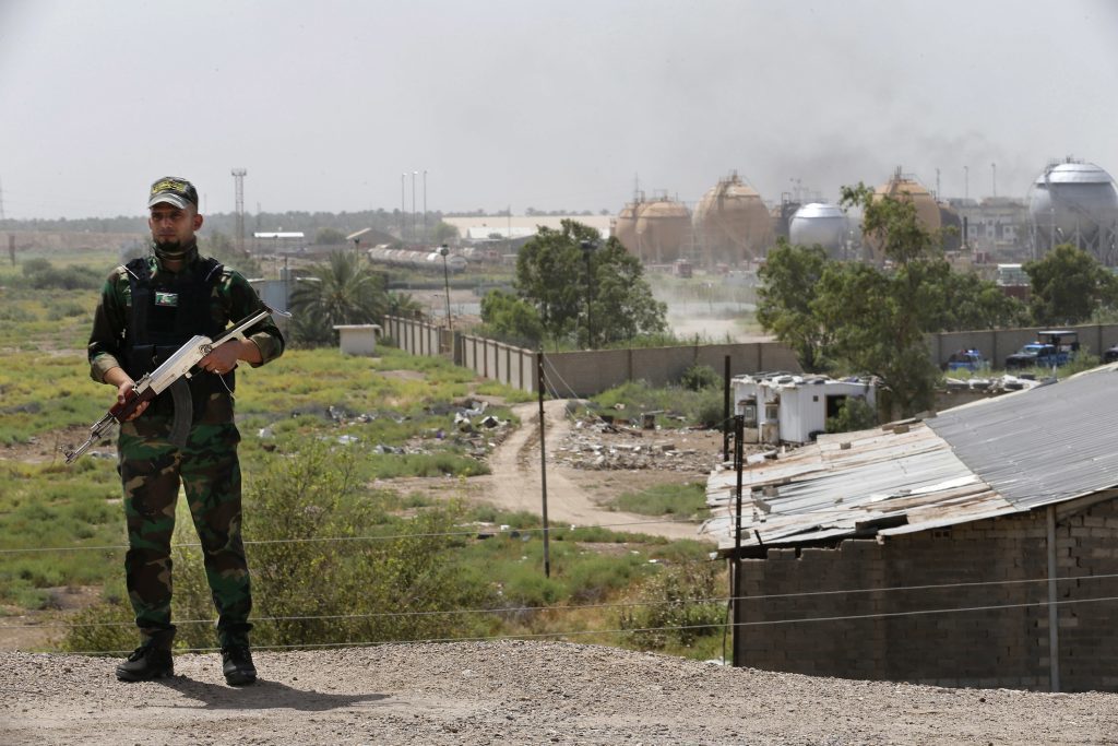 A federal police man stands guard outside the natural gas plant in Taji, 12 miles (20 kilometers) north of Baghdad, Iraq, Sunday, May 15, 2016. The Islamic State group launched a coordinated assault Sunday on a natural gas plant north of the capital that killed more than a dozen people, according to Iraqi officials.