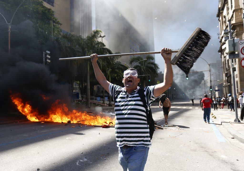 A man holds a broom as he shouts during clashes with police outside the state legislature during a protest against austerity measures being discussed in the chamber, in Rio de Janeiro, Brazil, Tuesday, Dec. 6, 2016. Legislators were voting on measures to address the state’s deepening financial crisis, in which thousands of state employees and retirees have not been paid or have been paid months late.