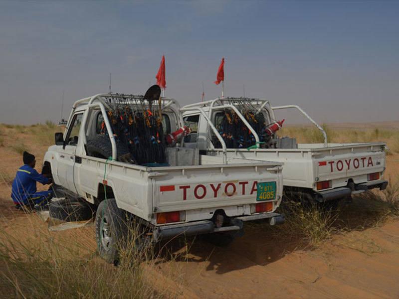 Two Toyota pickups on a sandy road