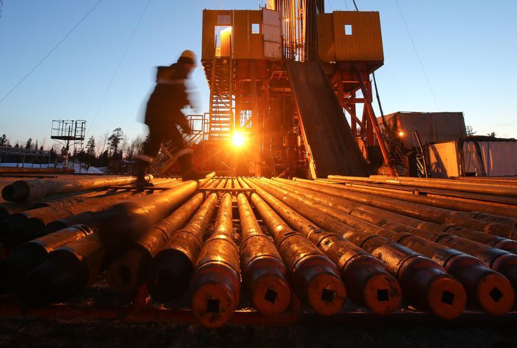 A worker passes an illuminated oil drilling rig, operated by Rosneft PJSC, in the Samotlor oilfield near Nizhnevartovsk, Russia. Photographer: Andrey Rudakov/Bloomberg