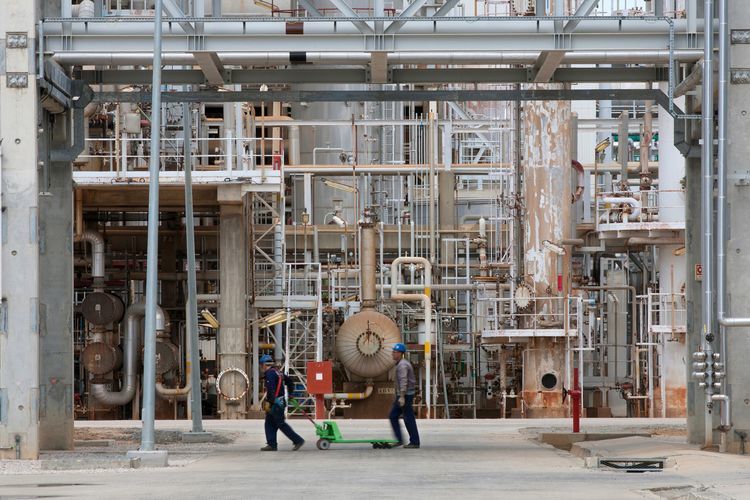 Employees walk past pipework at oil refining plant. Photographer: Mario Proenca/Bloomberg
