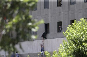 A man hands a child to a security guard from Iran's parliament building after an assault of several attackers, in Tehran, Iran, Wednesday, June 7, 2017. Suicide bombers and gunmen stormed into Iran's parliament and targeted the shrine of Ayatollah Ruhollah Khomeini on Wednesday, killing a security guard and wounding 12 other people in rare twin attacks, with the siege at the legislature still underway. (Fars News Agency, Omid Vahabzadeh via AP)